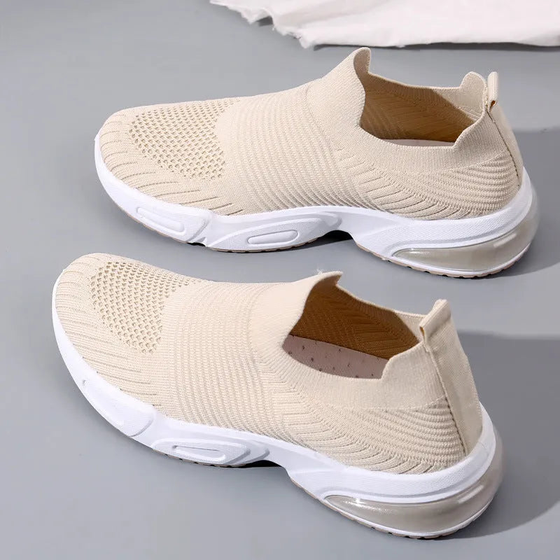A pair of low-top slip-on sock shoes with a mesh upper and PVC sole on a plain background.