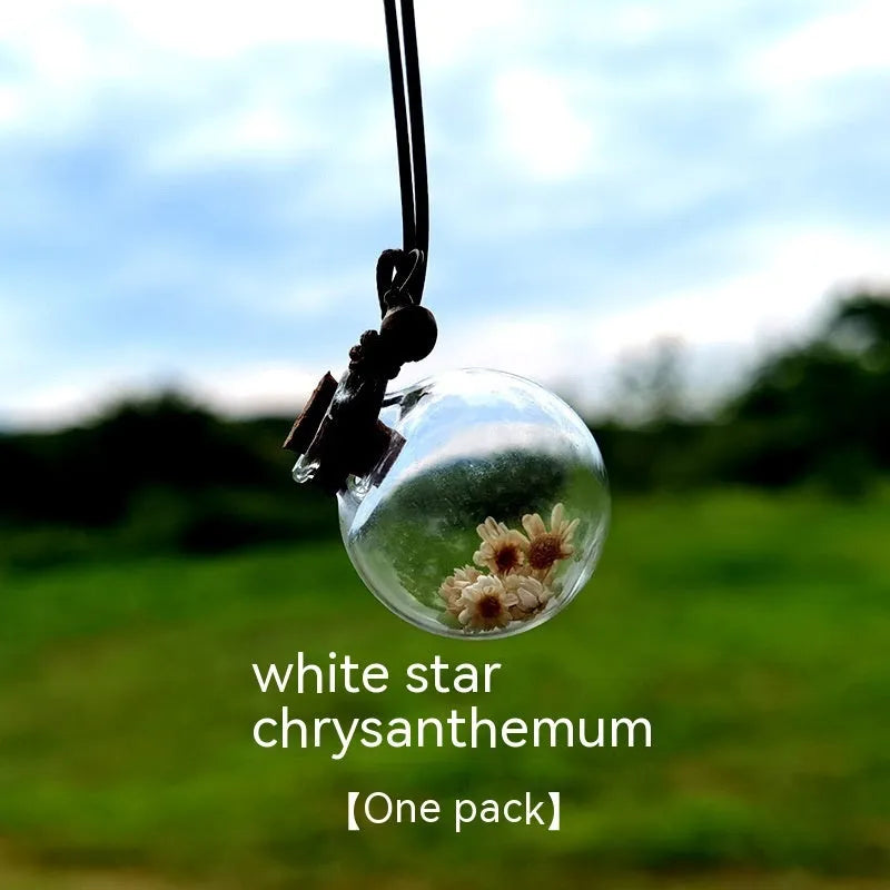 Glass car perfume pendant with preserved flower decoration hanging in car interior