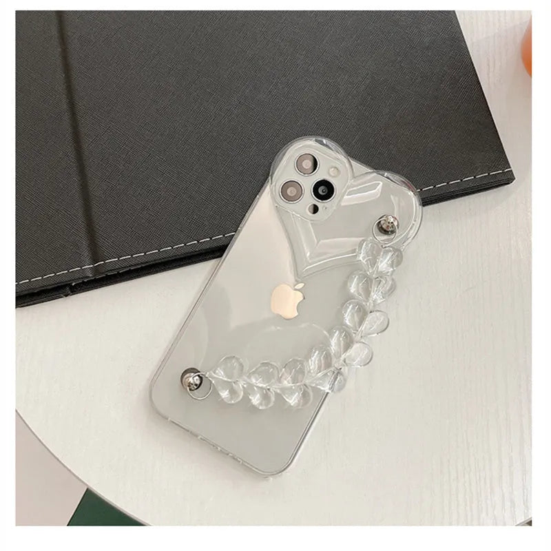 Clear iPhone case with transparent love heart bracelet charm attached, showing soft TPU material.