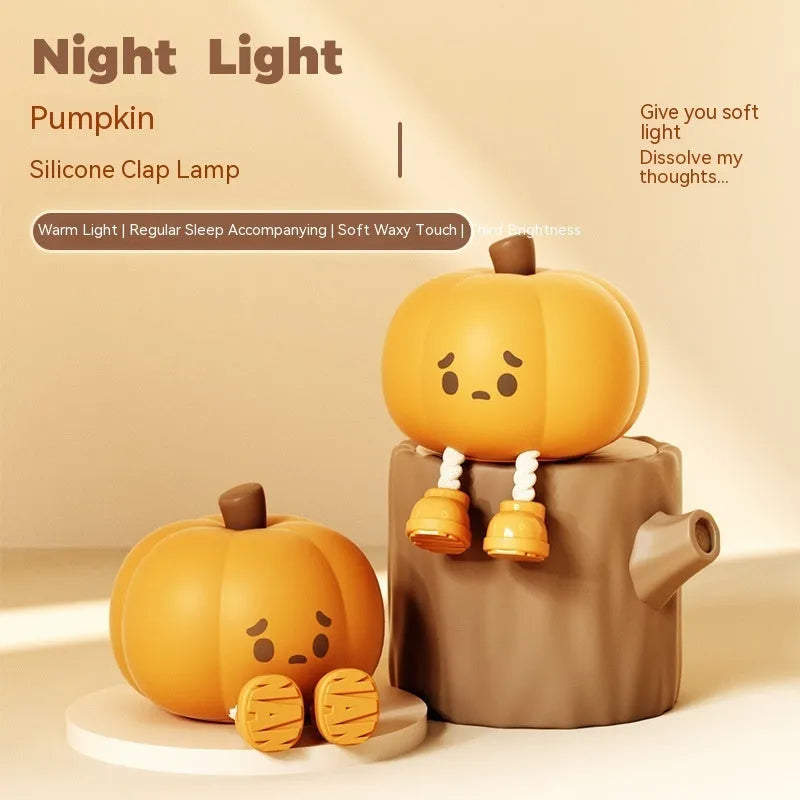 Soft orange pumpkin-shaped silicone night light with a warm glow, showing its compact size on a table.