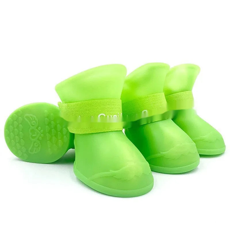 Set of four soft-soled rubber pet rain shoes in assorted colours on a grey background.