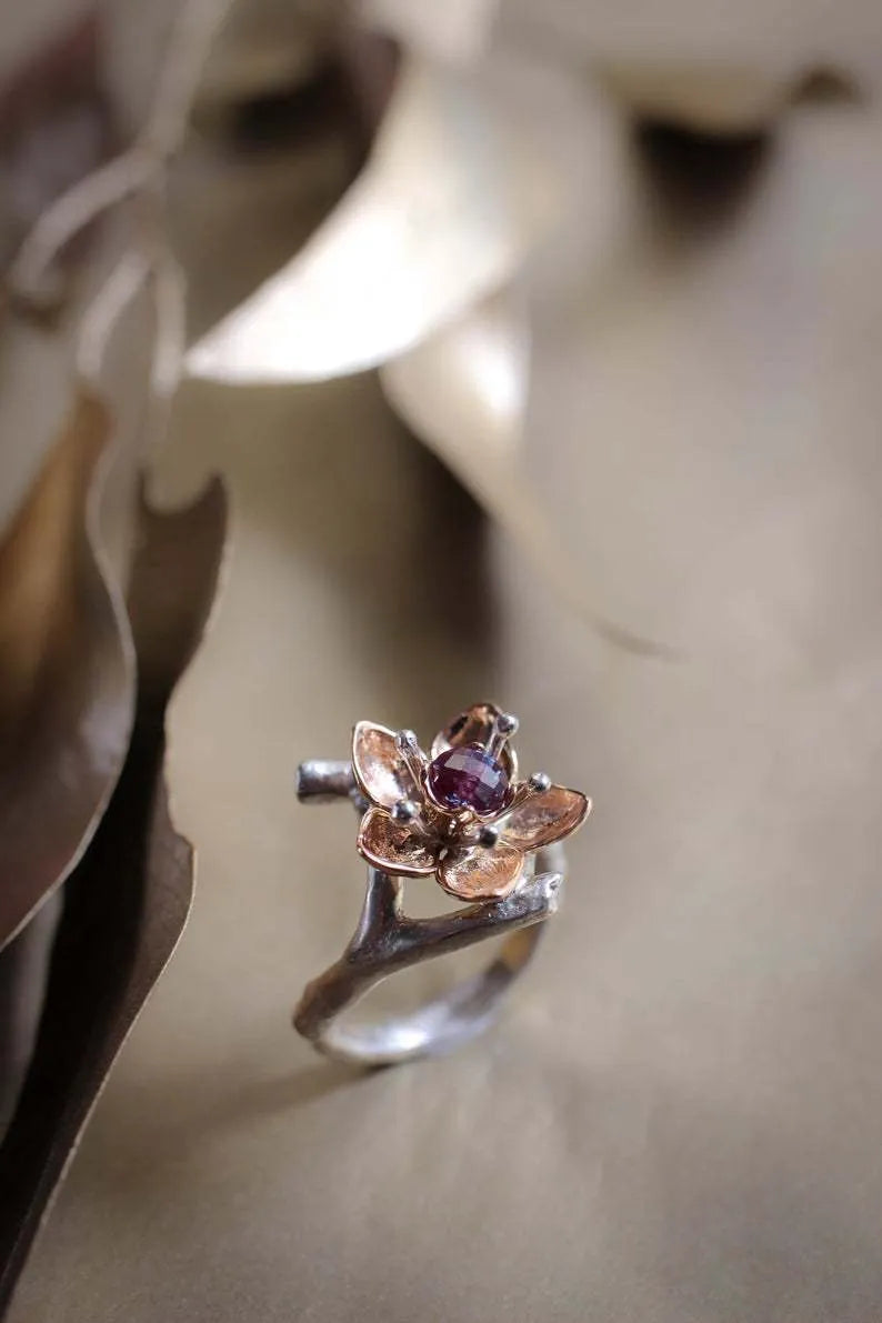 Silver two-tone women's ring with a geometric shape and floral design details on a plain background.