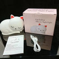 Sleepy cat silicone night light with warm white glow, induction pat feature, on a bedside table