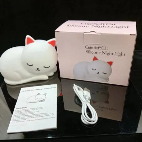 Sleepy cat silicone night light with warm white glow, induction pat feature, on a bedside table