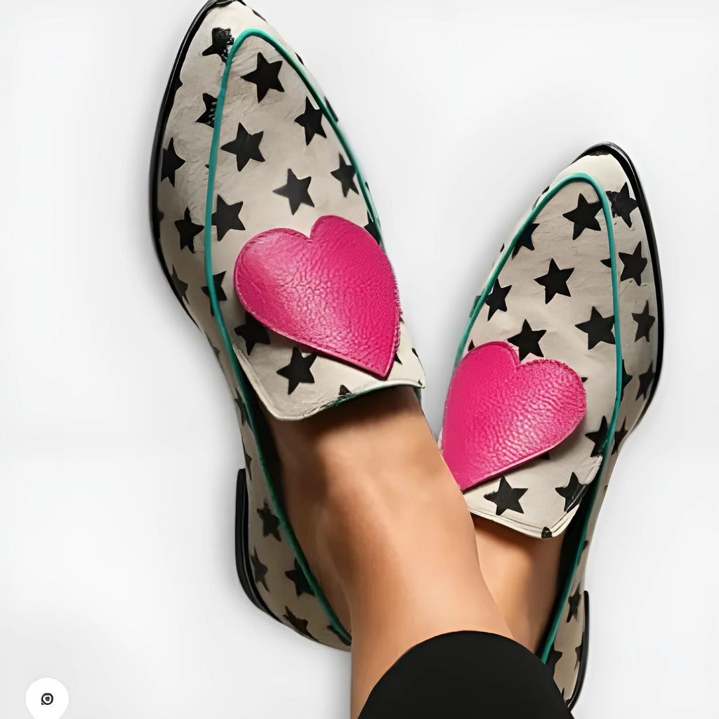 White low heel pointed-toe women's shoes with heart and star details on a solid background