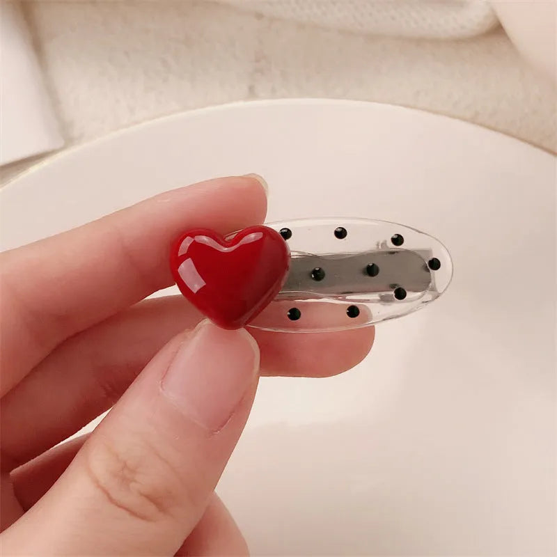 Red love heart-shaped plastic hair clip with retro dots and a willow leaf silhouette on a white background.