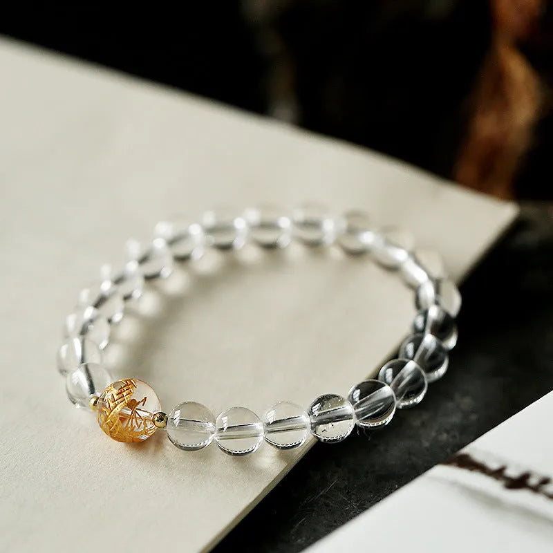Geometric obsidian and white crystal bracelet with a golden dragon focal bead on a wrist.