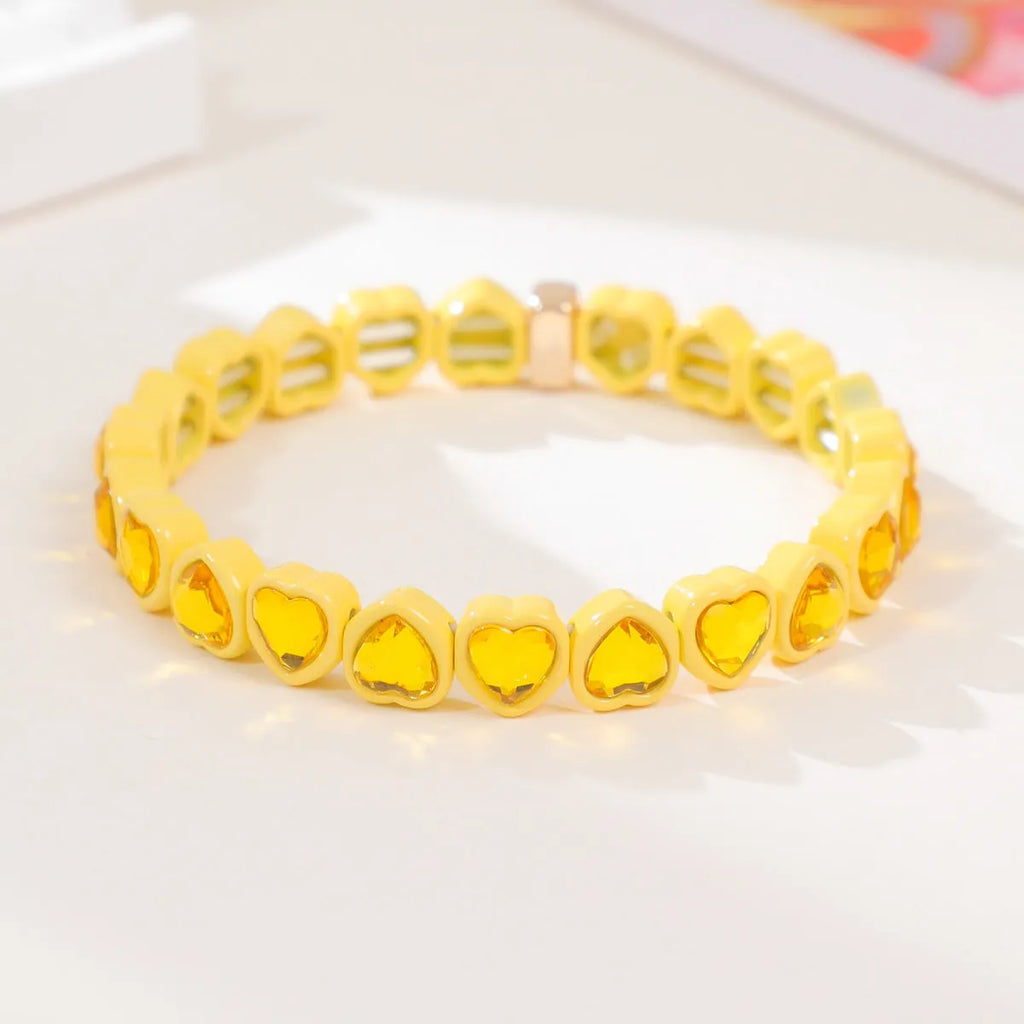 Colourful rainbow enamel heart-shaped stretch bracelet on a wrist.