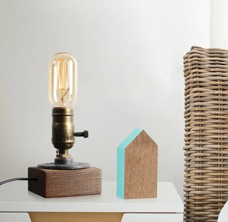 Water pipe table lamp with wood and iron construction, 9 cm wide, 13 cm high, on a wooden bedside table
