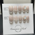 Women's short blush-coloured press-on artificial nails laid out in sizes XS, S, M, and L.