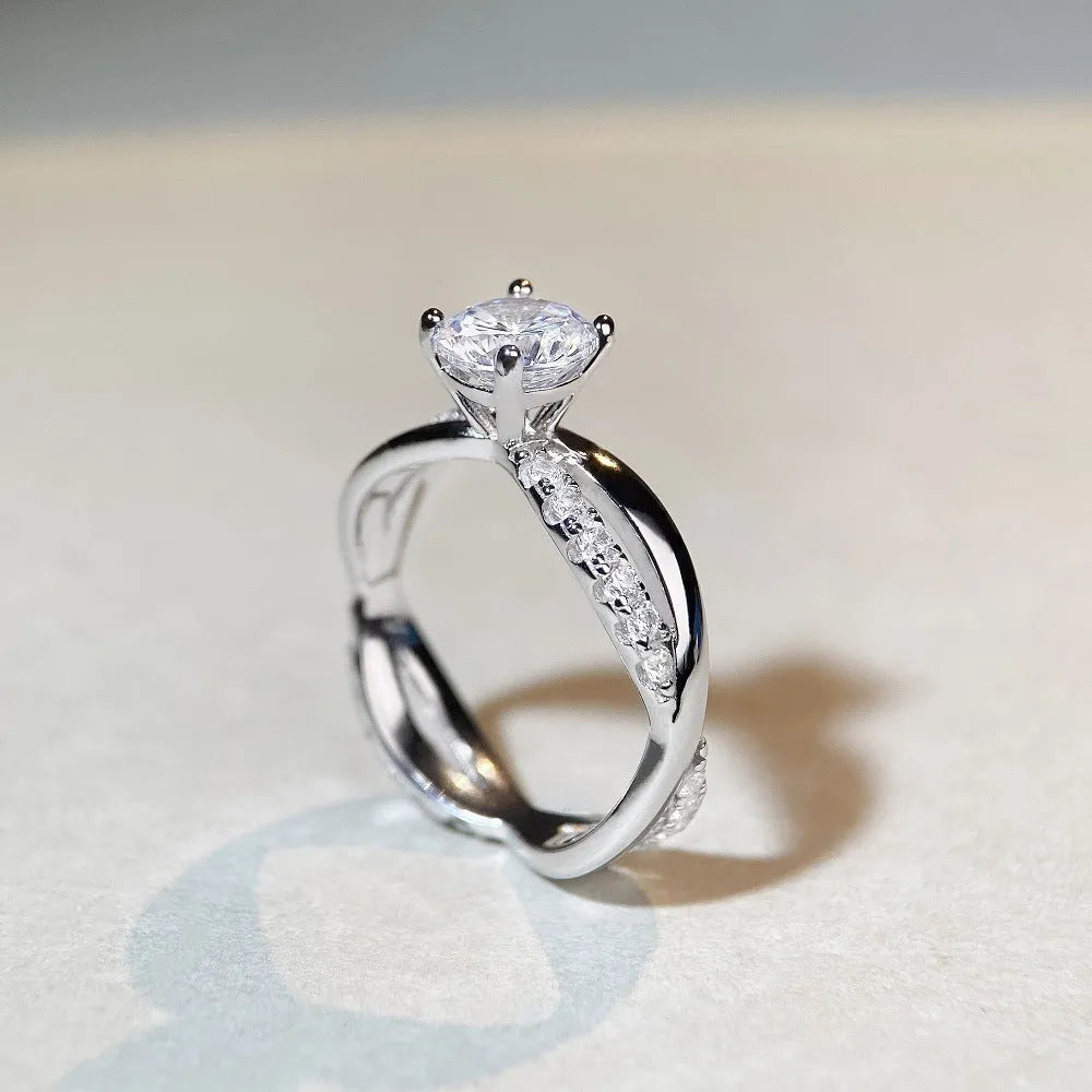 Silver geometric cross ring with a 1-karat moissanite stone on a twisted band.