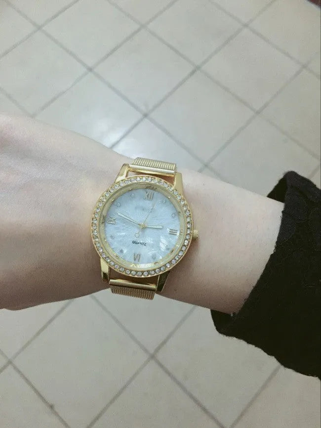 Golden mesh strap alloy electronic watch with round dial and world time GMT functions on a plain background