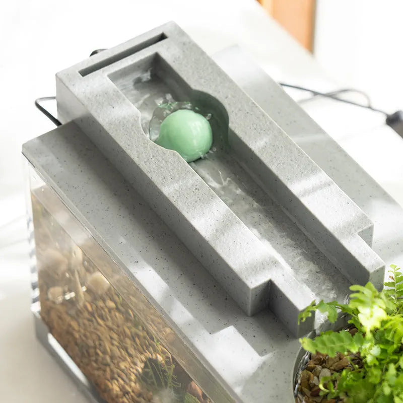 Small stone trough plastic fish tank with water pump and built-in light on a desk
