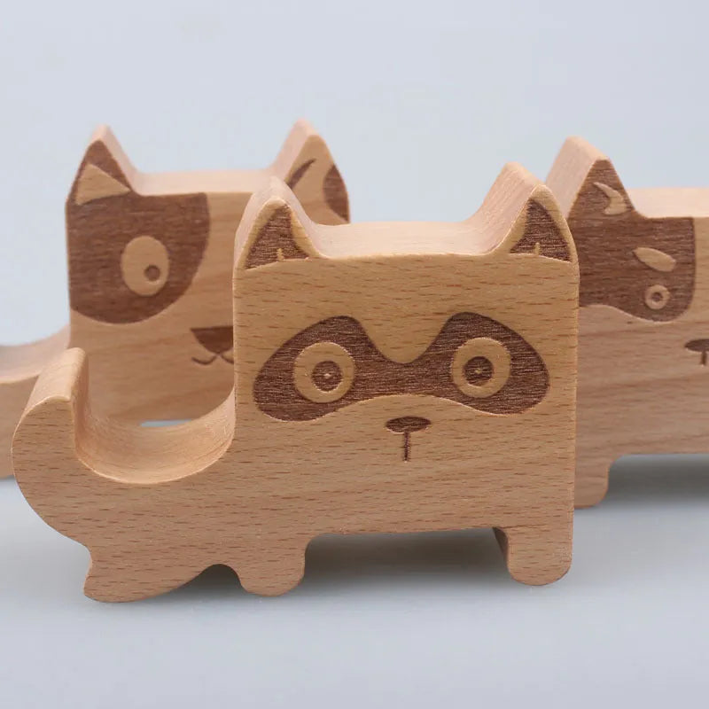 Beech wood and resin lazy bracket mobile phone holder in an animal design style on a desk.