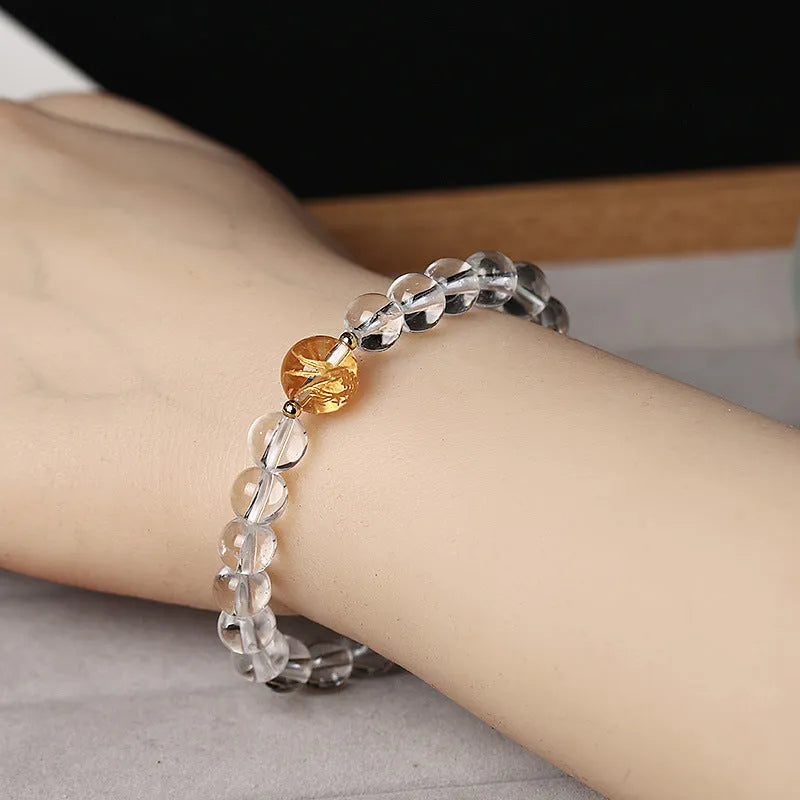 Geometric obsidian and white crystal bracelet with a golden dragon focal bead on a wrist.