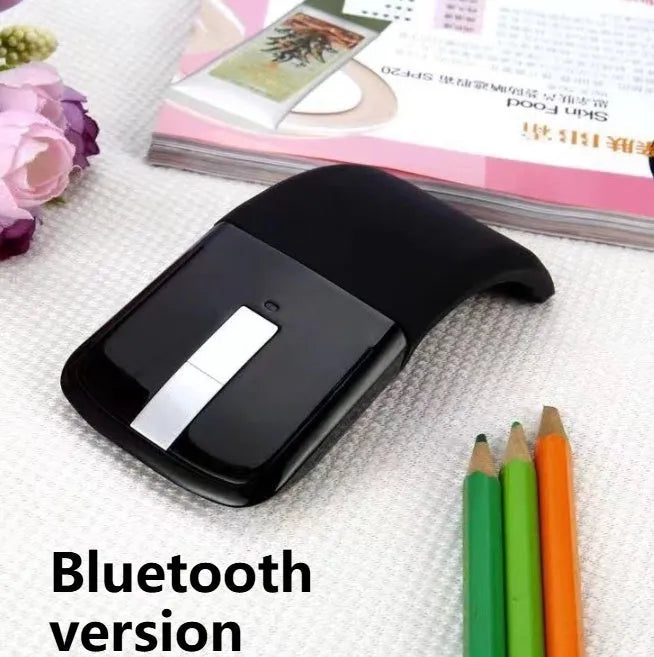 Black folding Bluetooth wireless mouse shown both folded and unfolded beside laptop