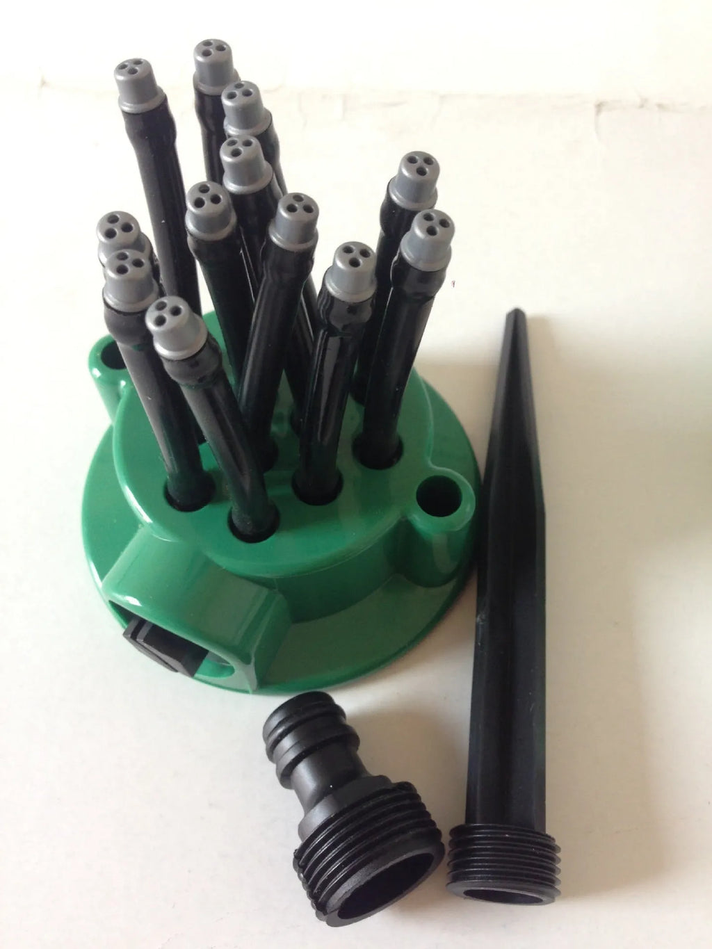 Green plastic adjustable lawn sprinkler with multiple bendable spray arms on a 9cm base.