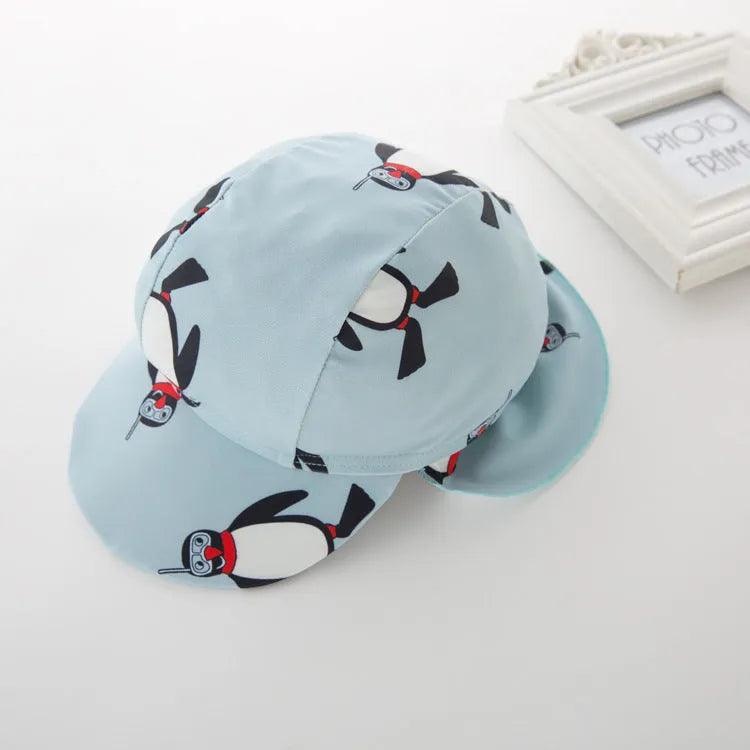 Boys' blue and white penguin print long sleeve swimsuit with matching swimming cap laid flat.