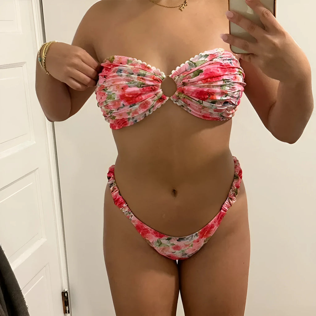 Women's floral print tube top bikini set with lace detailing on a blue background.