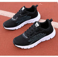 Women's low-top platform running sneakers in black and white colours with round toe and cross strap design
