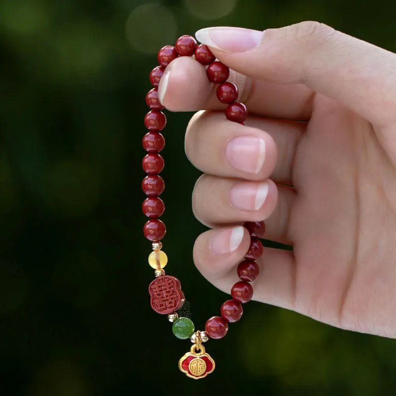 Emperor sandstone bracelet with fu charm on wrist, showing cinnabar and stone beads.