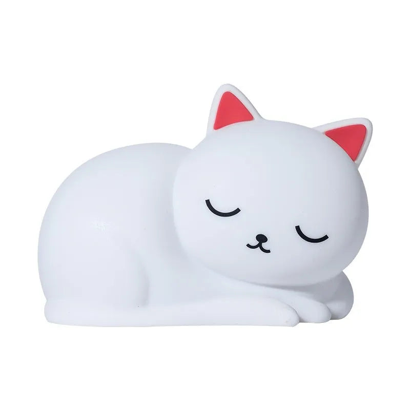 Sleepy cat silicone night light with warm white glow, induction pat feature, on a bedside table