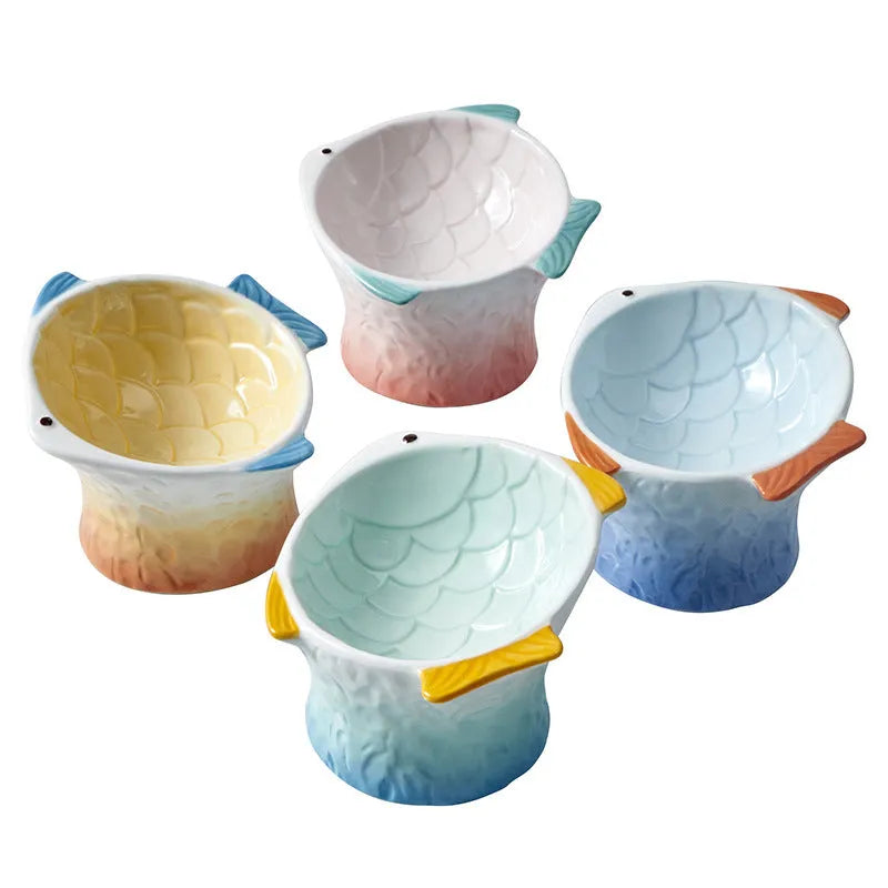 Set of four blue fish-shaped ceramic cat bowls with tilted, elevated design on a table.