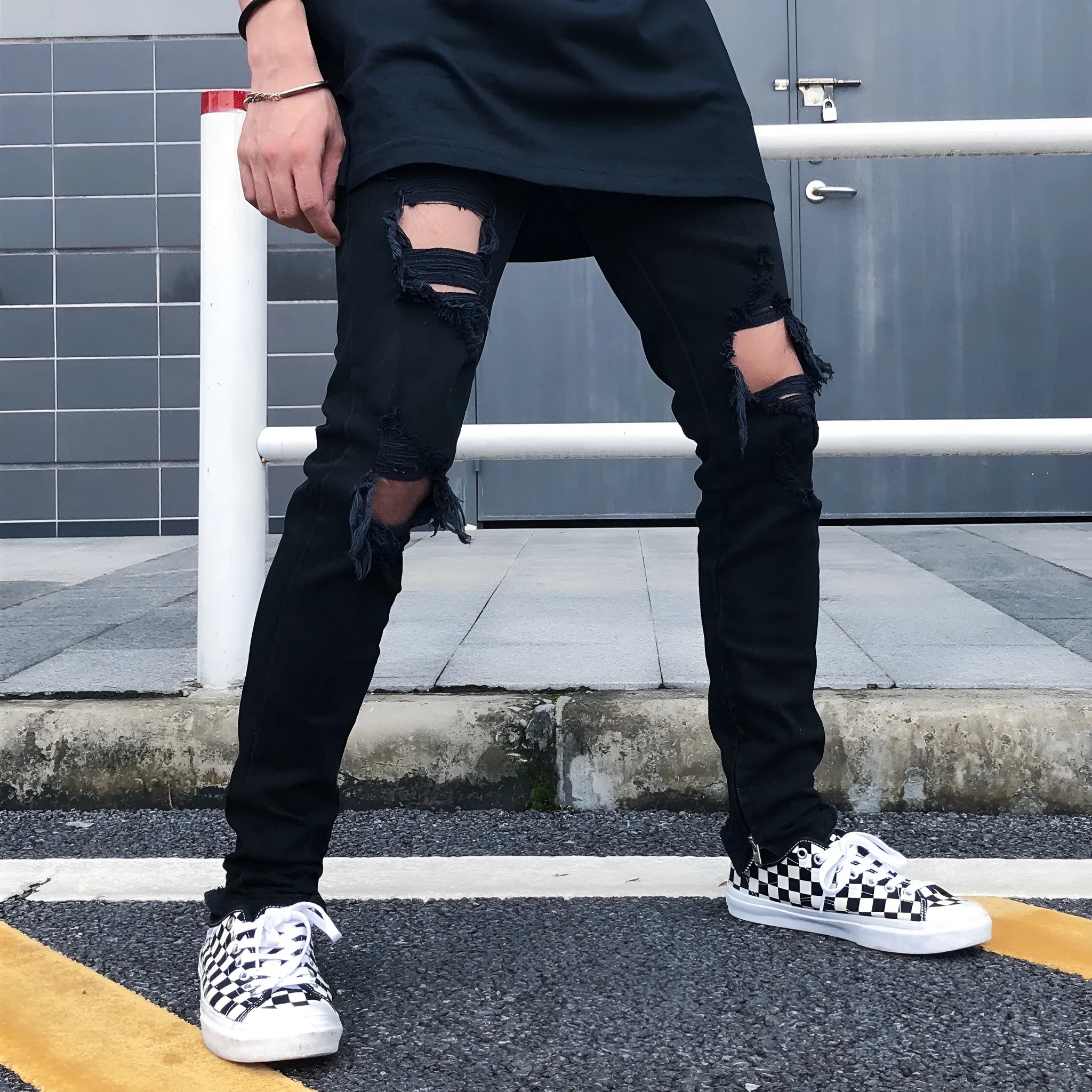 Men's high street style black torn jeans in washed black denim with raw edge details, front view.