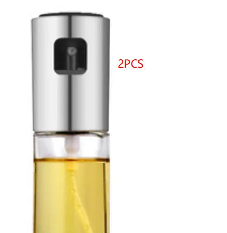 Gold pump-action oil and vinegar spray bottle with 100ml glass body on kitchen counter.