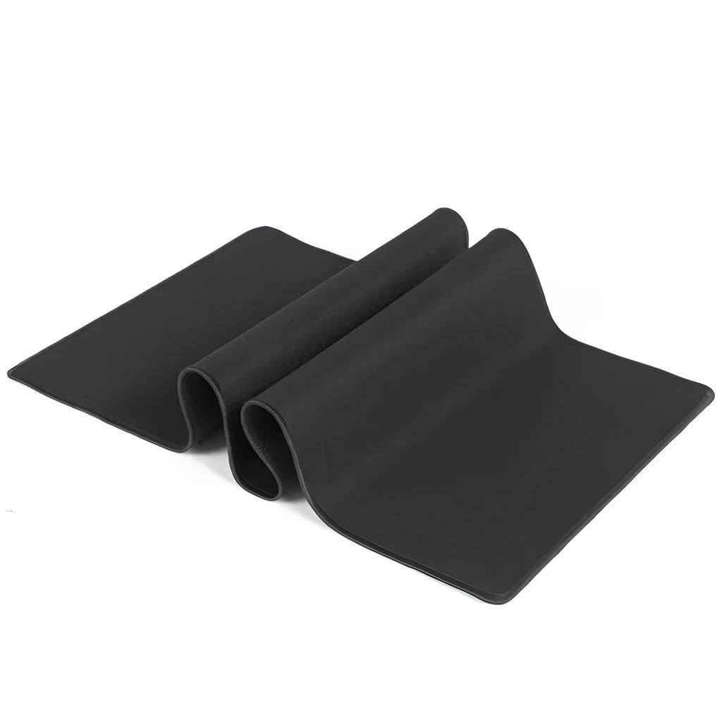 Long black desk pad with stitched edges on a wooden desk, with keyboard and mouse placed on top.