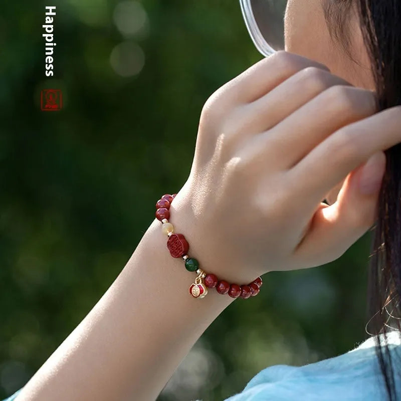 Emperor sandstone bracelet with fu charm on wrist, showing cinnabar and stone beads.