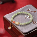 Women's jade bracelet with gold-plated gourd charm and Fu character pendant on a 6mm bead.