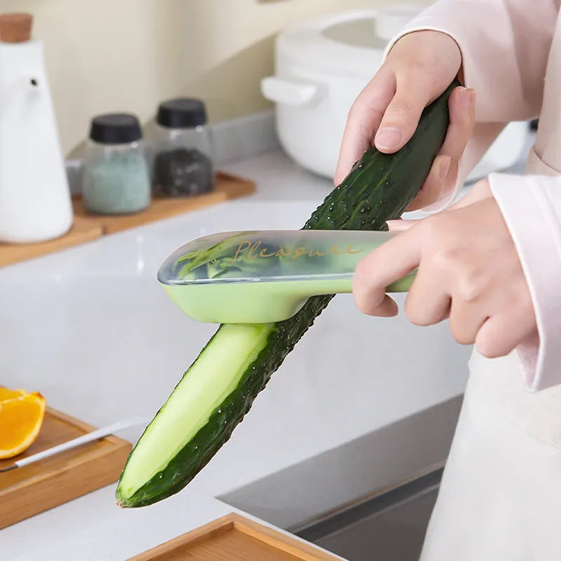 Dark green kitchen peeler with storage tube showing stainless steel blade and hanging hole on handle