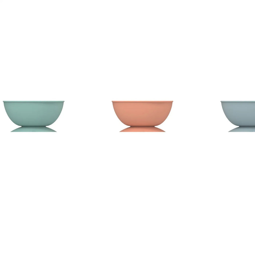 Cyan silicone dog bowl with textured slow feeder patterns and a suction cup base on a table.