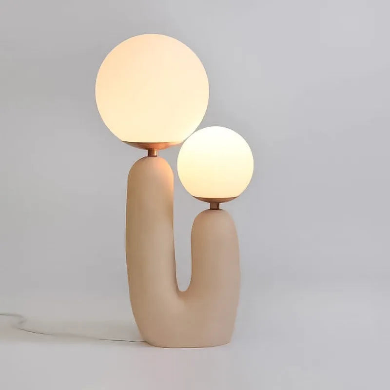 Pink double-head resin table lamp with glass shade on a bedside table, 49cm tall