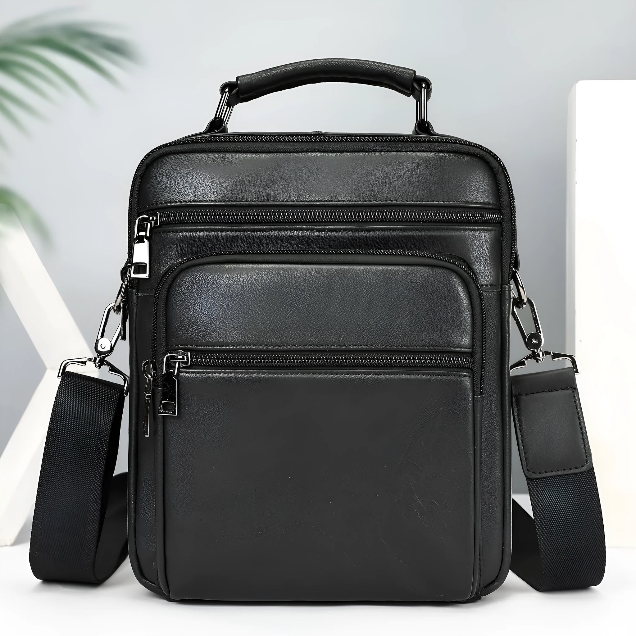 Men's genuine leather messenger bag in black with visible sewing line details and shoulder strap