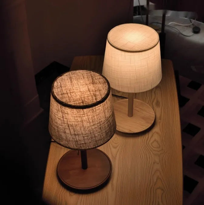 Walnut coloured solid wood bedside lamp with a white cloth shade and a cable switch.