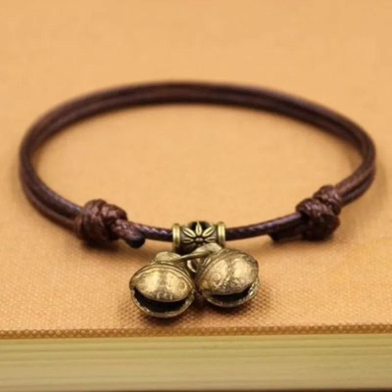Adjustable black nylon dog collar with a brass bell for a small pet.