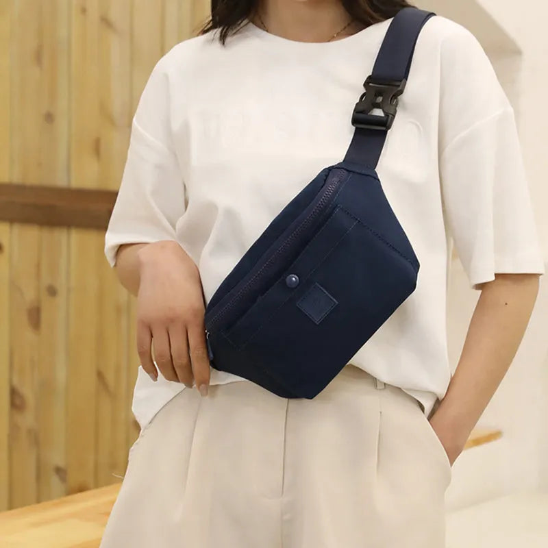 Women's nylon crossbody fanny pack in black with zippered compartments and letter detail.