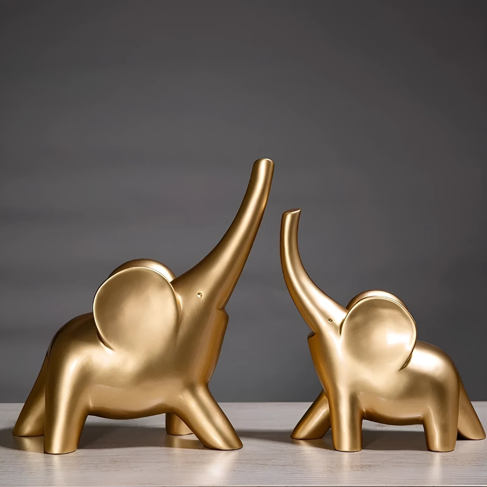 Modern resin elephant ornament in rose gold colour with raised trunk on display surface