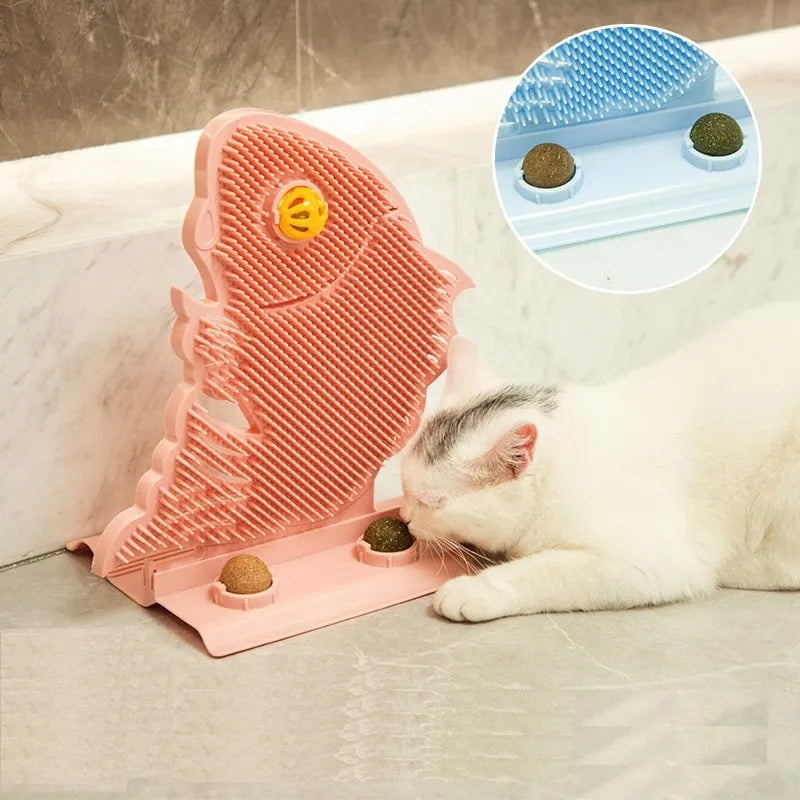 Blue plastic fish-shaped cat wall scratcher with brush, two green catnip balls, a bell, and a mounting base.