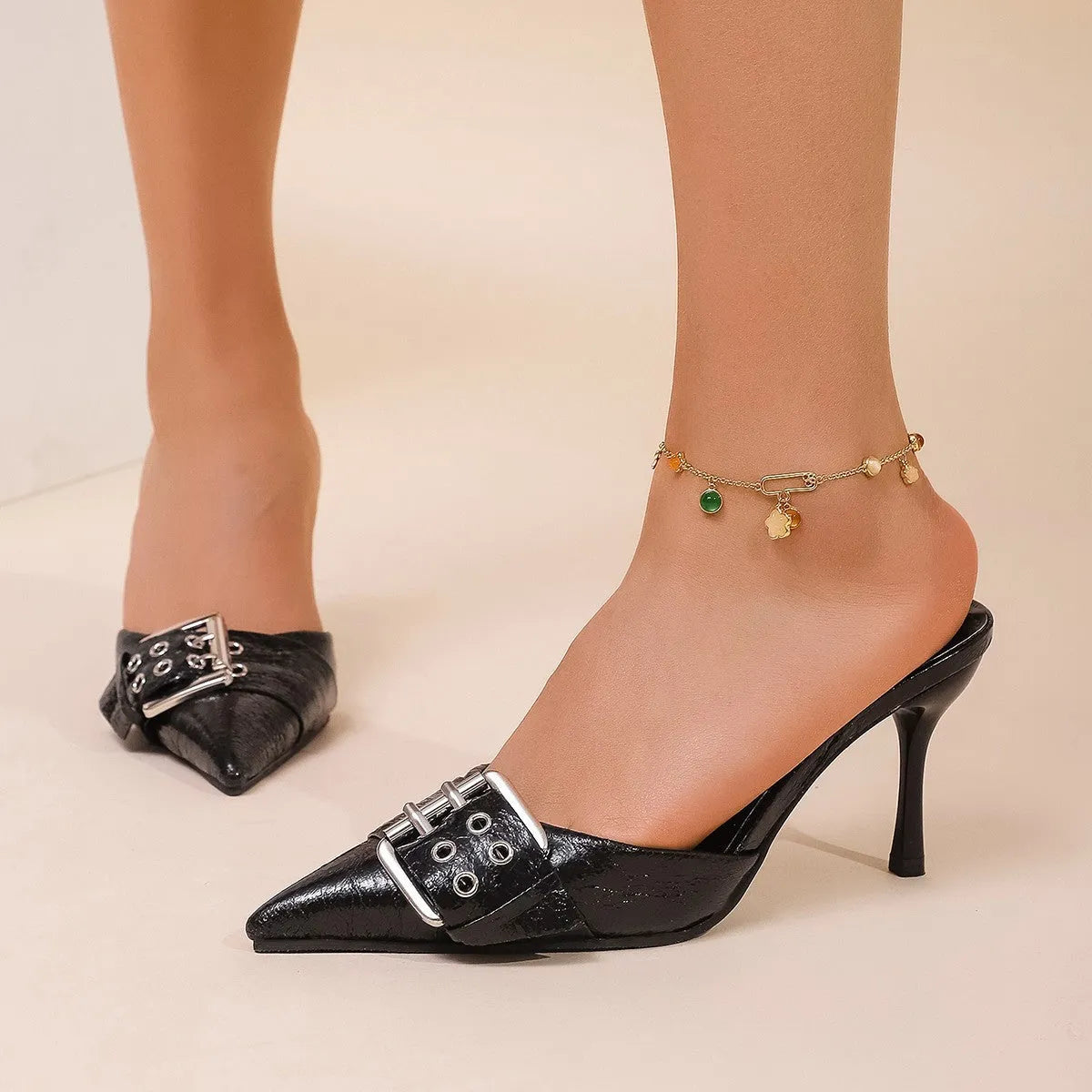 Black women's pointed toe high heels with a strap and buckle closure.