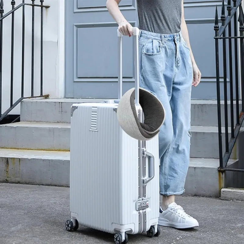 U-shaped memory foam travel neck pillow rolled up next to its carry bag, showing navy blue and grey colour options.