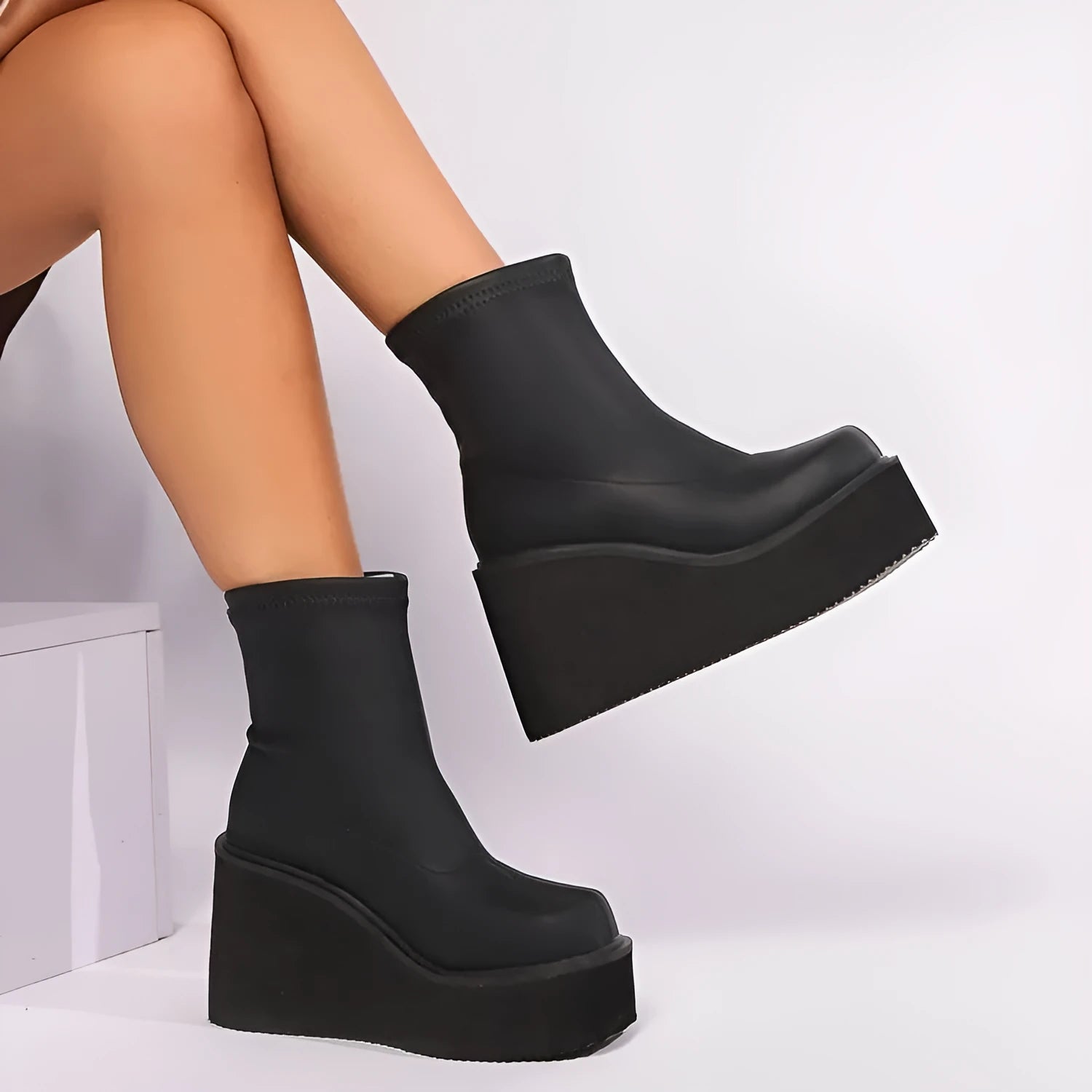 Plus size black wedge heel ankle boots with a round toe and waterproof platform on a wooden floor.