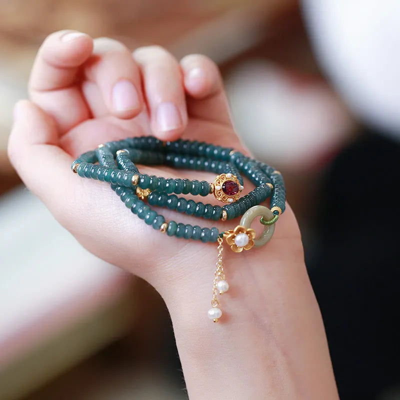 Blue water abacus and jade bead bracelet with tourmaline rings and pearl accents on a wrist.