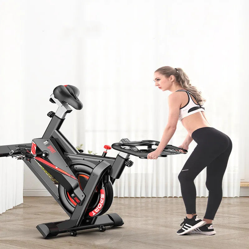 Black upright spinning bike with console and infinite resistance knob on a home gym floor