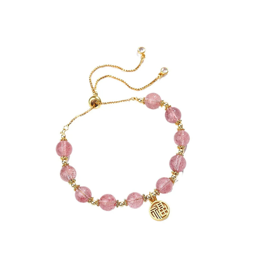 Close-up of a women's adjustable bracelet with pink strawberry quartz crystal beads and a silver fu charm on a geometric chain.