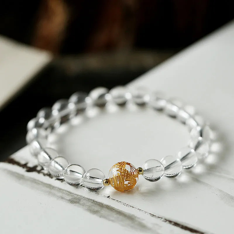 Geometric obsidian and white crystal bracelet with a golden dragon focal bead on a wrist.