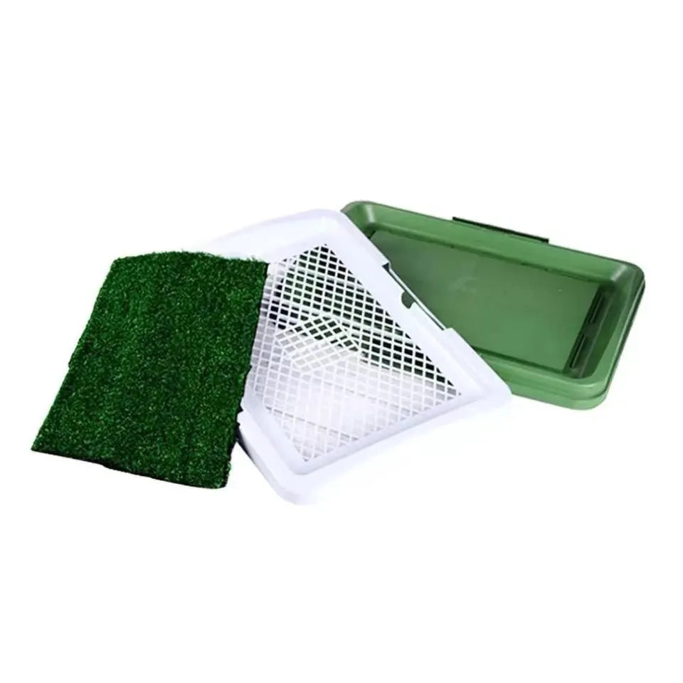Green artificial grass indoor dog toilet tray with drainage holes and absorbent pads for puppy training.