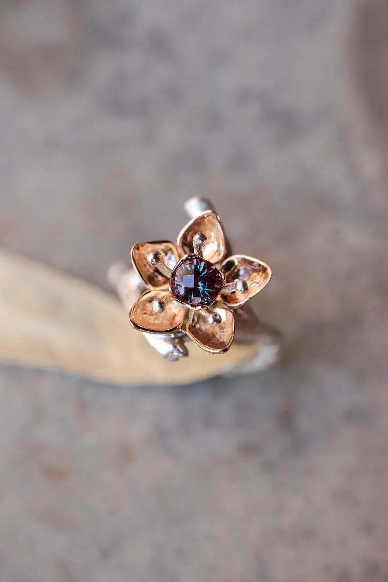 Silver two-tone women's ring with a geometric shape and floral design details on a plain background.